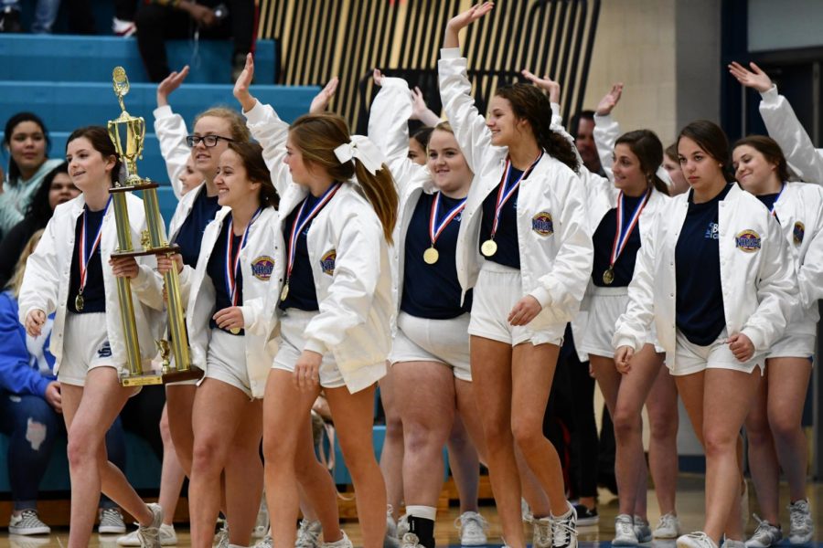 Clad in their white national champion jackets, the cheerleaders parade their trophy before the student body during a pep rally on Feb. 12. During the pep rally, they also performed their winning routine before the national championship banner was unveiled.