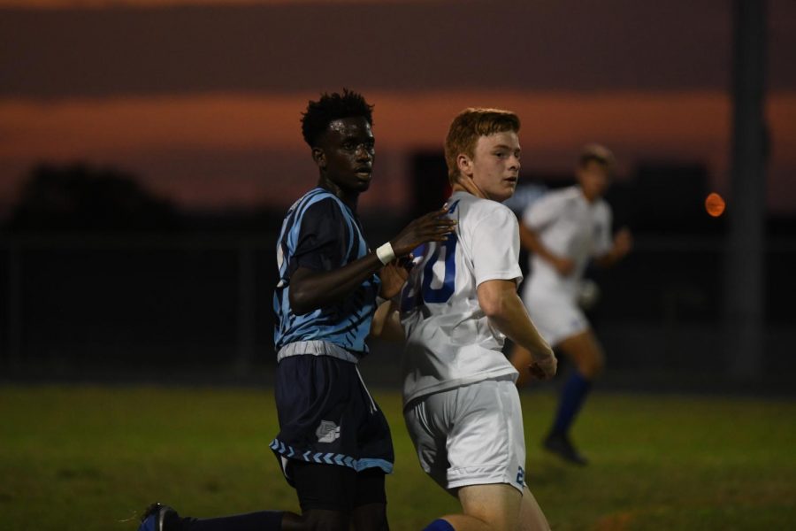 Dan Likiko runs behind a player, during the soccer game at Boone County high school on Oct. 3. 