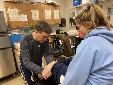 Boone athletic trainer Tom “Burnsy” Burns wraps the knee of sophomore softball player Abby Sproles before practice on Feb. 20. Burnsy has been serving Rebel athletes for 28 years.